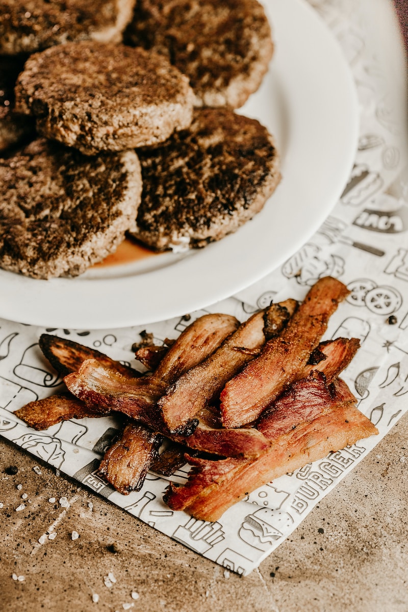 a white plate topped with bacon next to a pile of cookies