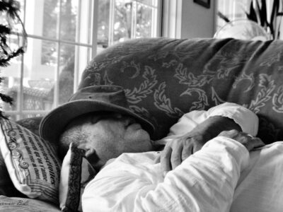 a man sitting on a couch wearing a hat