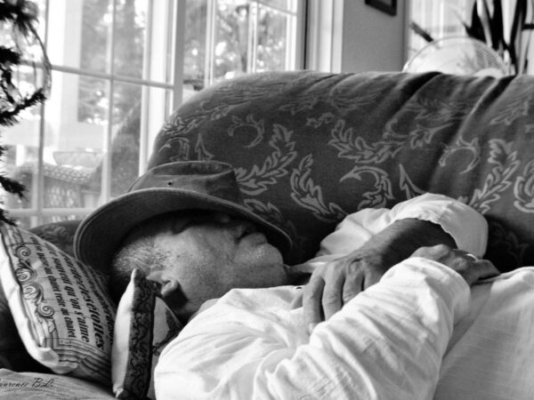 a man sitting on a couch wearing a hat